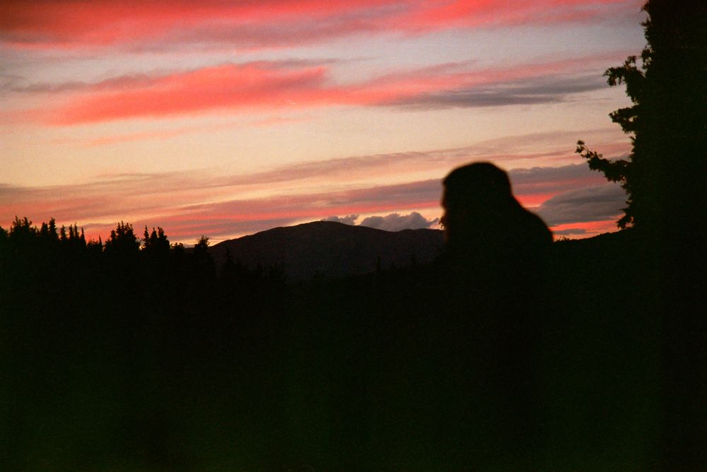 Silhouette of a person at sunset in a mountain landscape during golden hour.