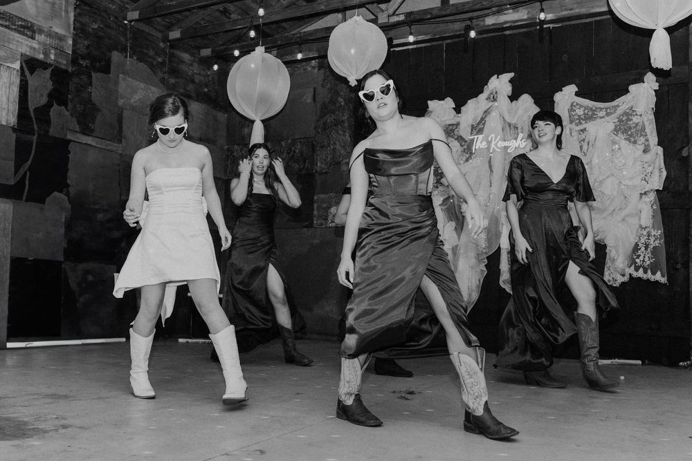 Black and white photo of wedding reception dance floor with guests celebrating.