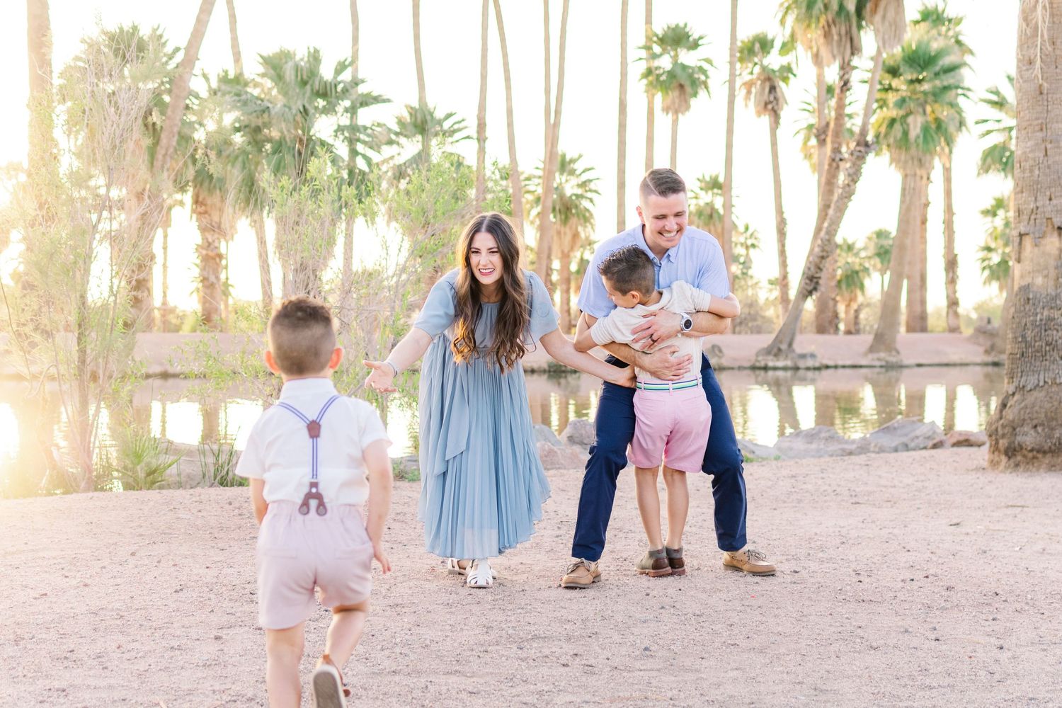 Light and airy portrait of a family of 4 in front of a pond at golden hour at Papago Park in Phoenix, Arizona.