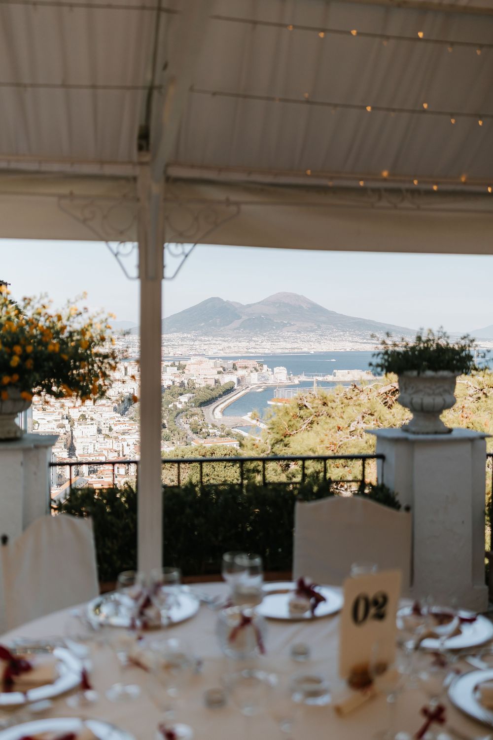 Panoramic mountain view through an elegant white-columned terrace with dining tables set for a special occasion.