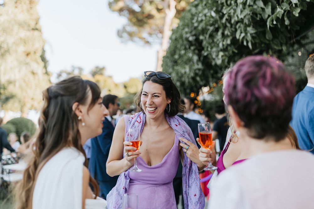 Guests mingle and socialize at an outdoor wedding reception during golden hour.