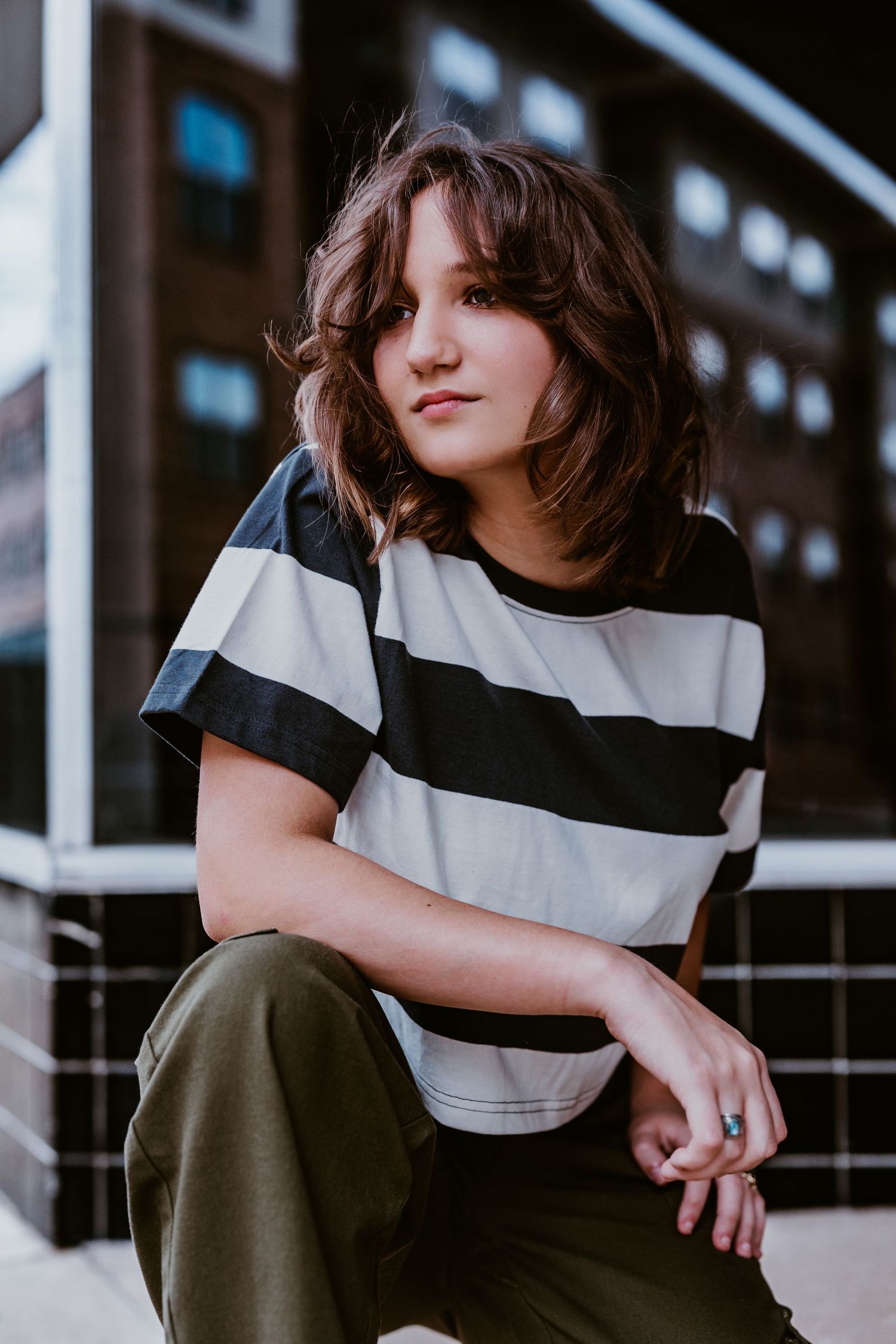 A casual portrait of someone in a black and white striped t-shirt against an urban background.