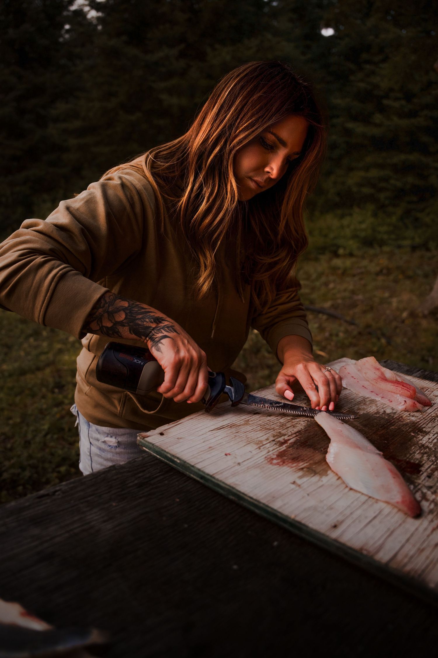Fresh fish being filleted on a wooden cutting board in dim lighting.