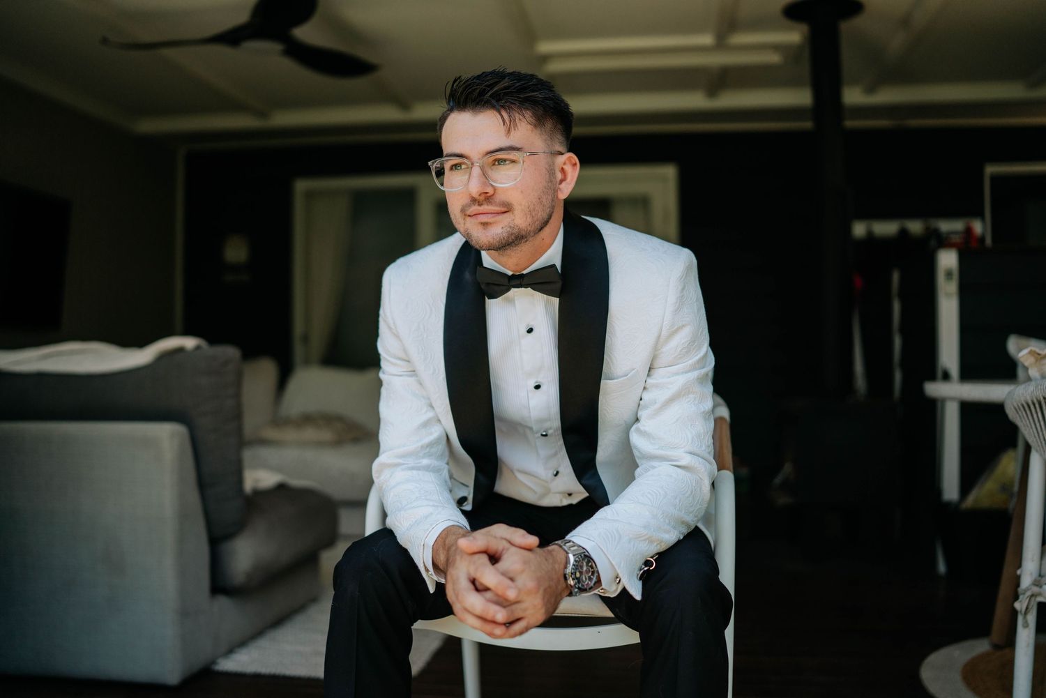Professional in a white blazer and black shirt sits at a table in a modern restaurant setting.