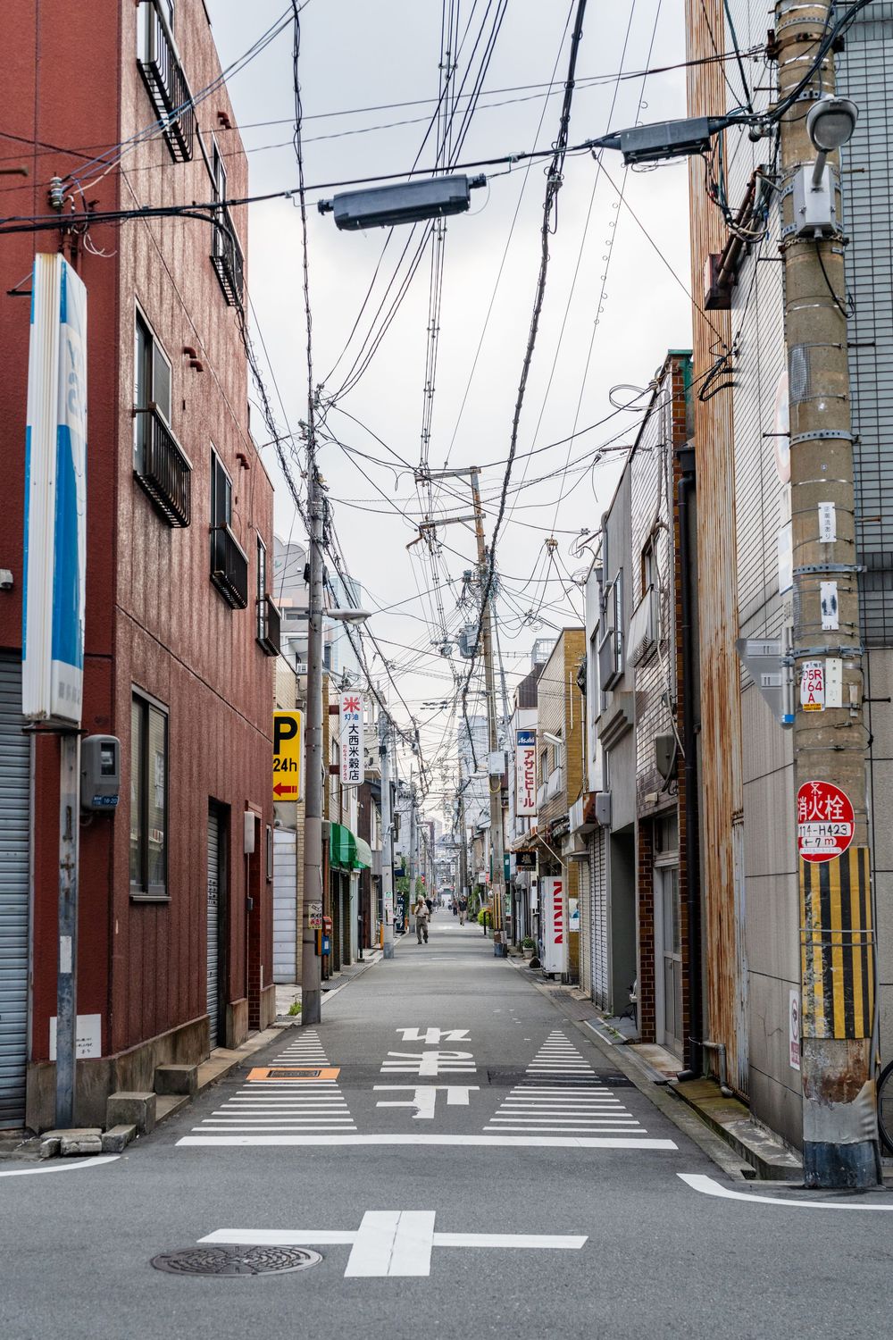 Empty Japanese street with power lines overhead and red brick buildings.