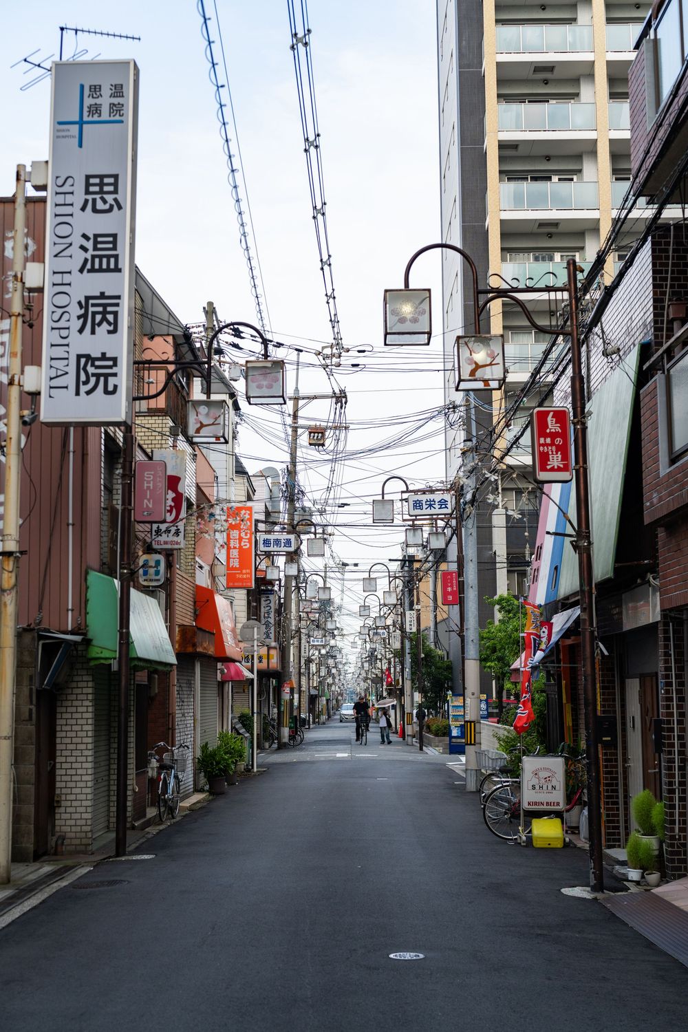 Quiet commercial street in Japan with shops and Japanese signage.