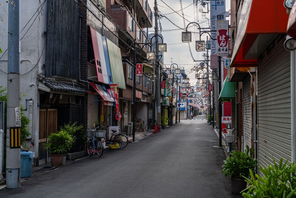 Commercial shopping street in Japan with closed storefronts and overhead wires.