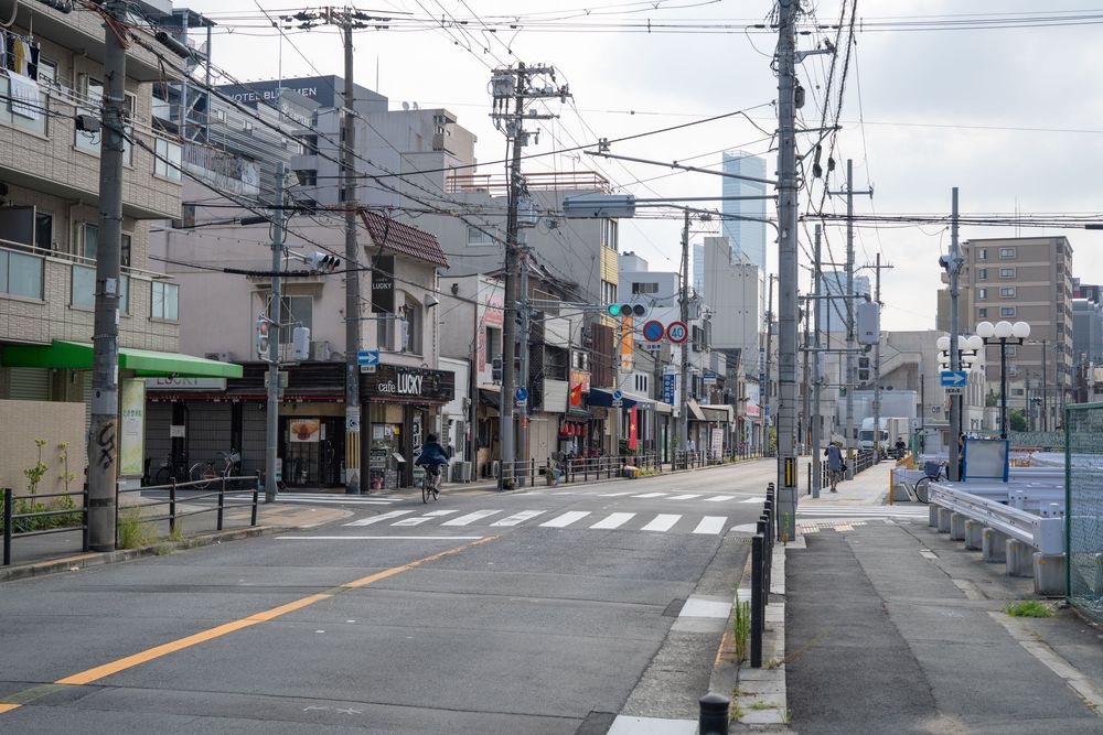 Wide urban street in Japan with utility poles and buildings lining both sides.
