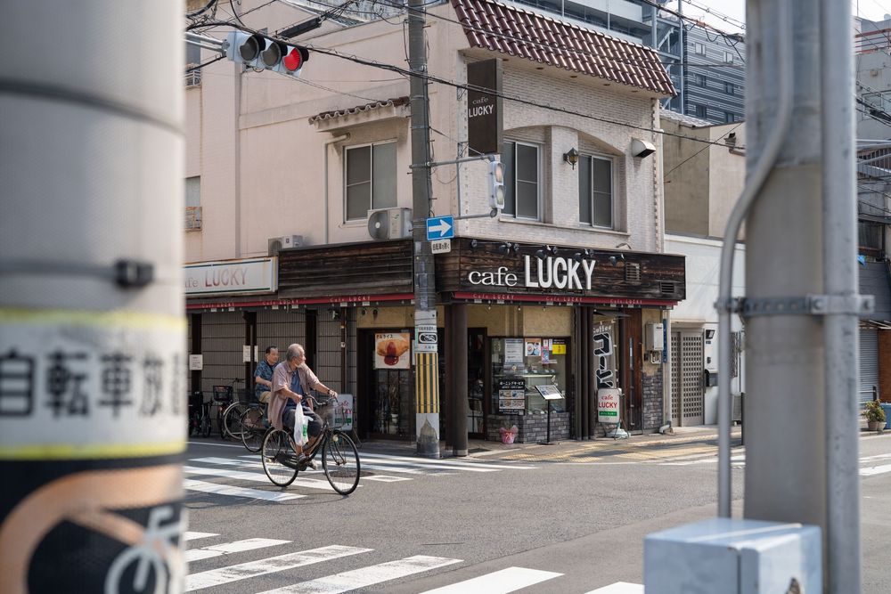 Japanese street corner with a shop called Lucky visible in the distance.