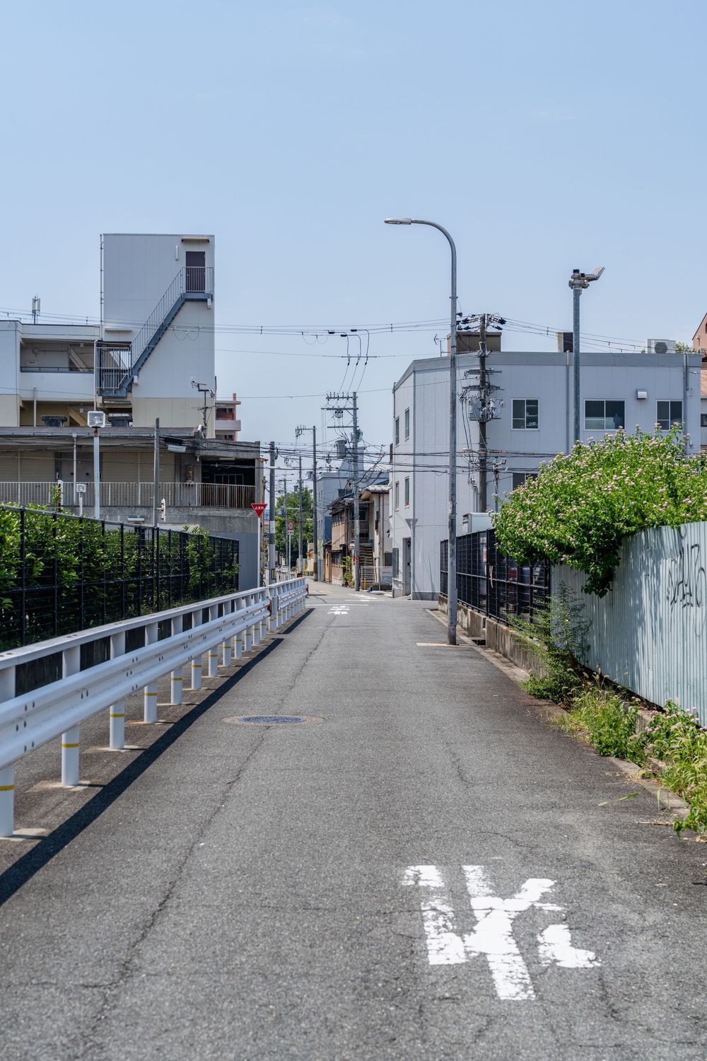 Elevated concrete walkway with white railings and buildings in the background.