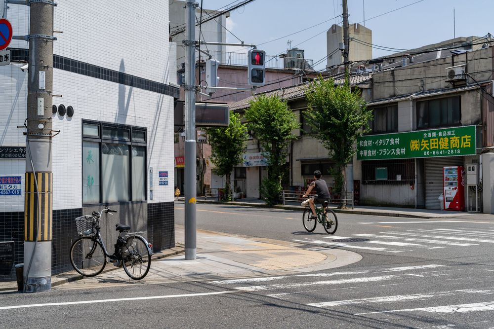 Urban intersection in Japan with traffic signals and commercial buildings.