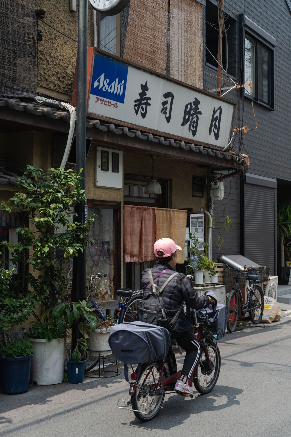 Parked bicycles line a quiet Japanese street with traditional storefronts and signage.