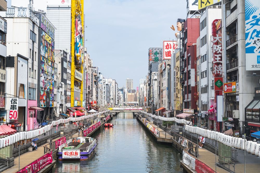 Iconic view of Dotonbori Canal in Osaka with neon signs and tall buildings reflecting on the water.
