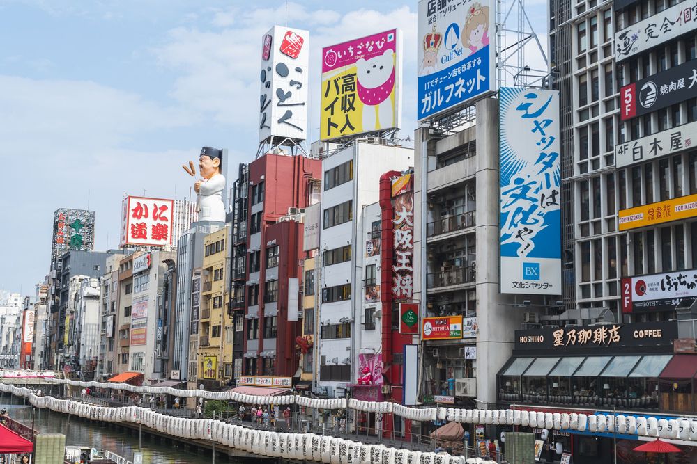 Vibrant commercial district in Osaka with colorful billboards and signage stretching down the street.