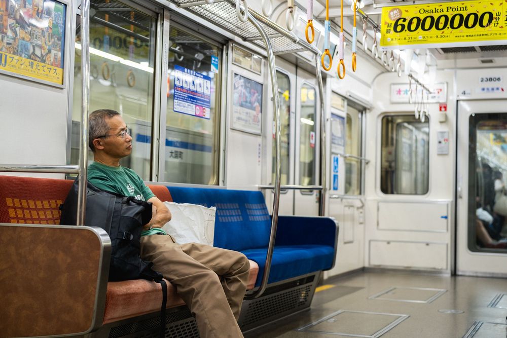 Interior of a clean, modern Japanese subway car with blue seats and advertisements.
