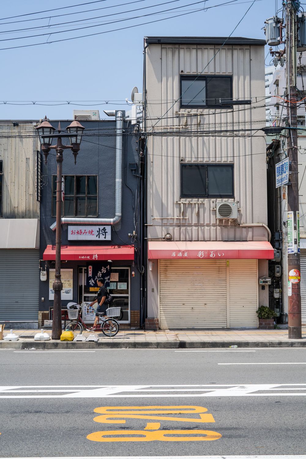 Empty Japanese street with painted bicycle lane markings and industrial buildings.