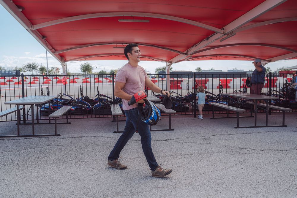 Go kart racing track with red barriers and concrete surface under blue sky.
