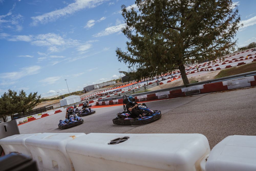 Go kart racing circuit with trees and buildings in background on sunny day.