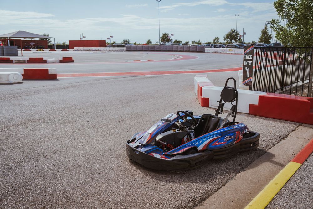 Racing go karts speeding around track with red and white safety barriers.