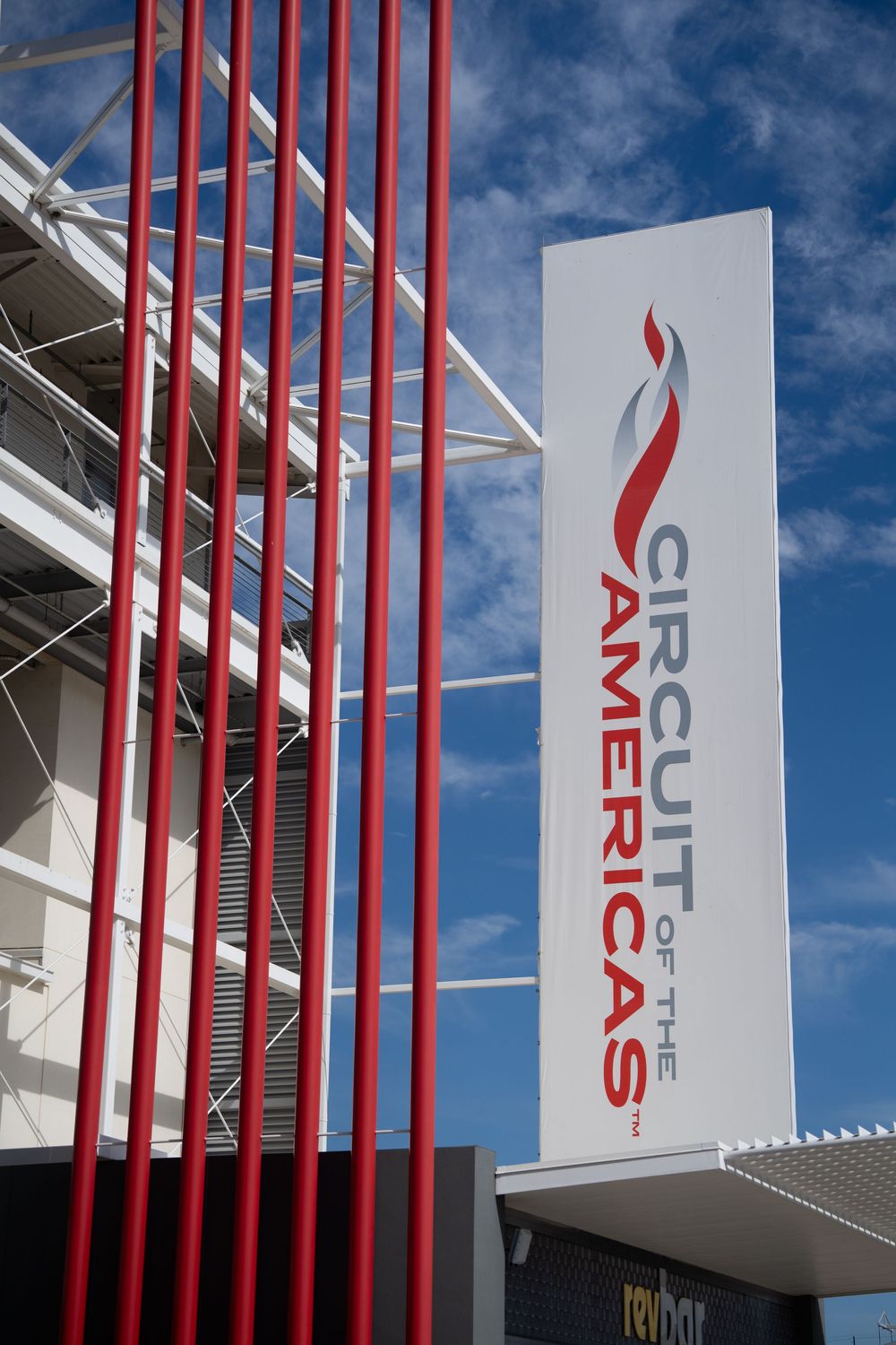 Modern building exterior with red vertical architectural elements against blue sky.