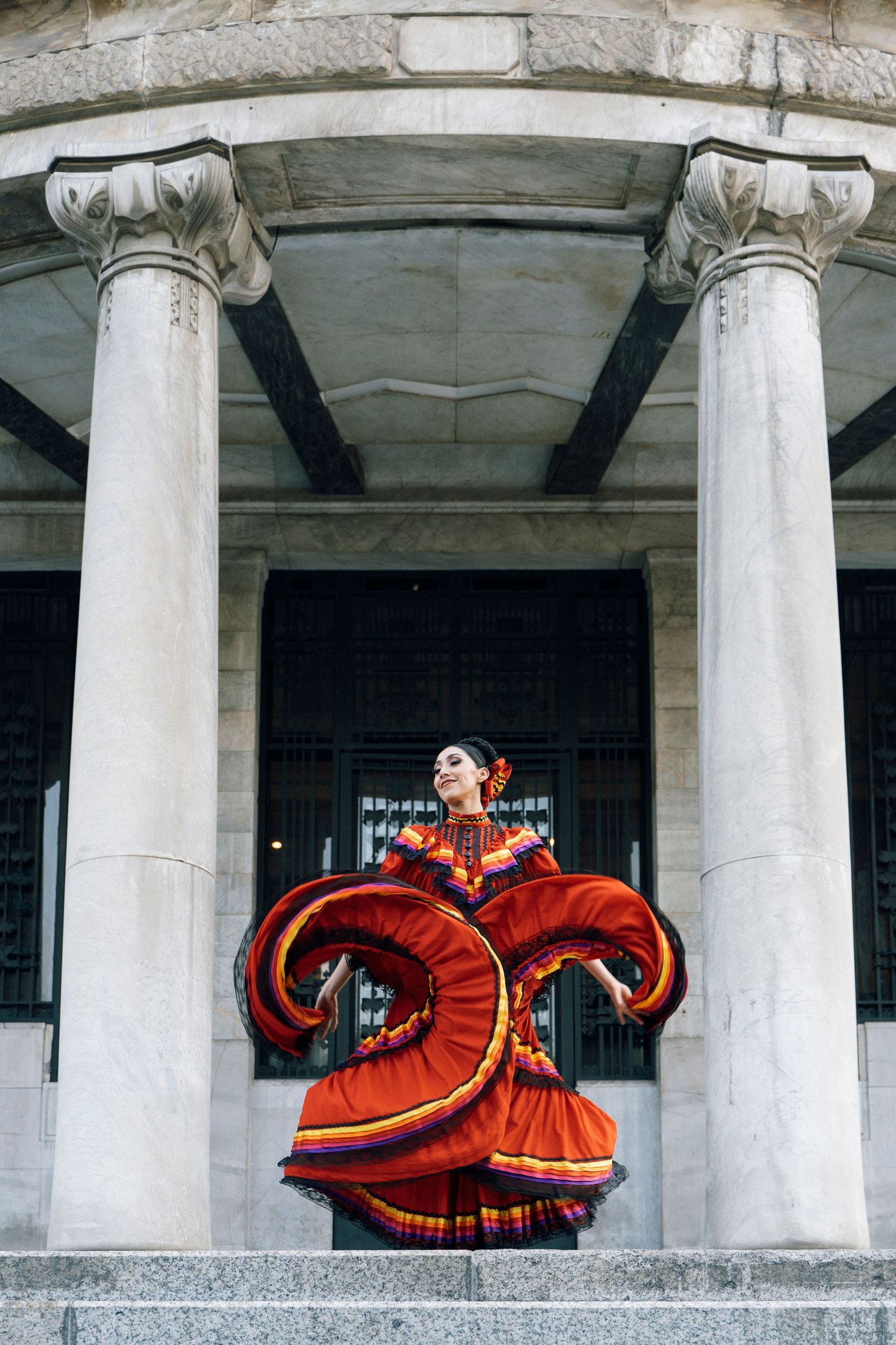 Ballet Folklórico dancer performing expressive movement in front of Palacio de Bellas Artes