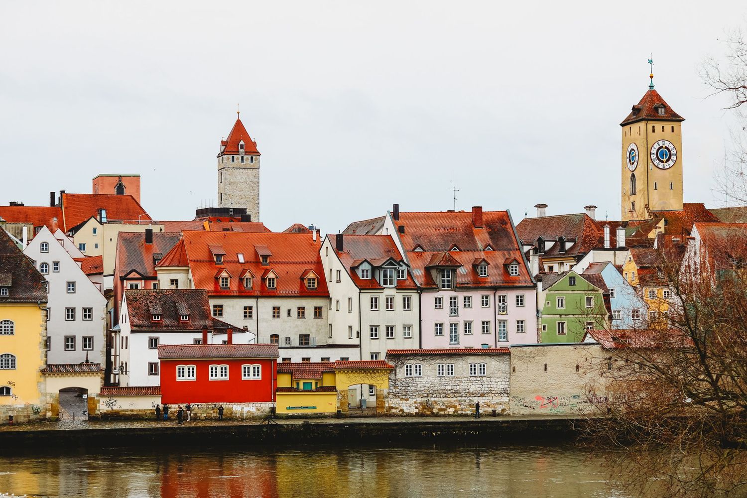 Panoramic view of colorful European coastal town buildings with red roofs along waterfront.