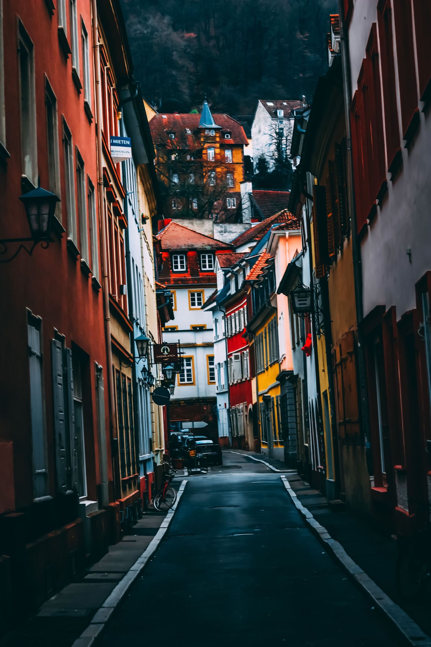 Narrow cobblestone street lined with red and pastel buildings in a quaint European town.