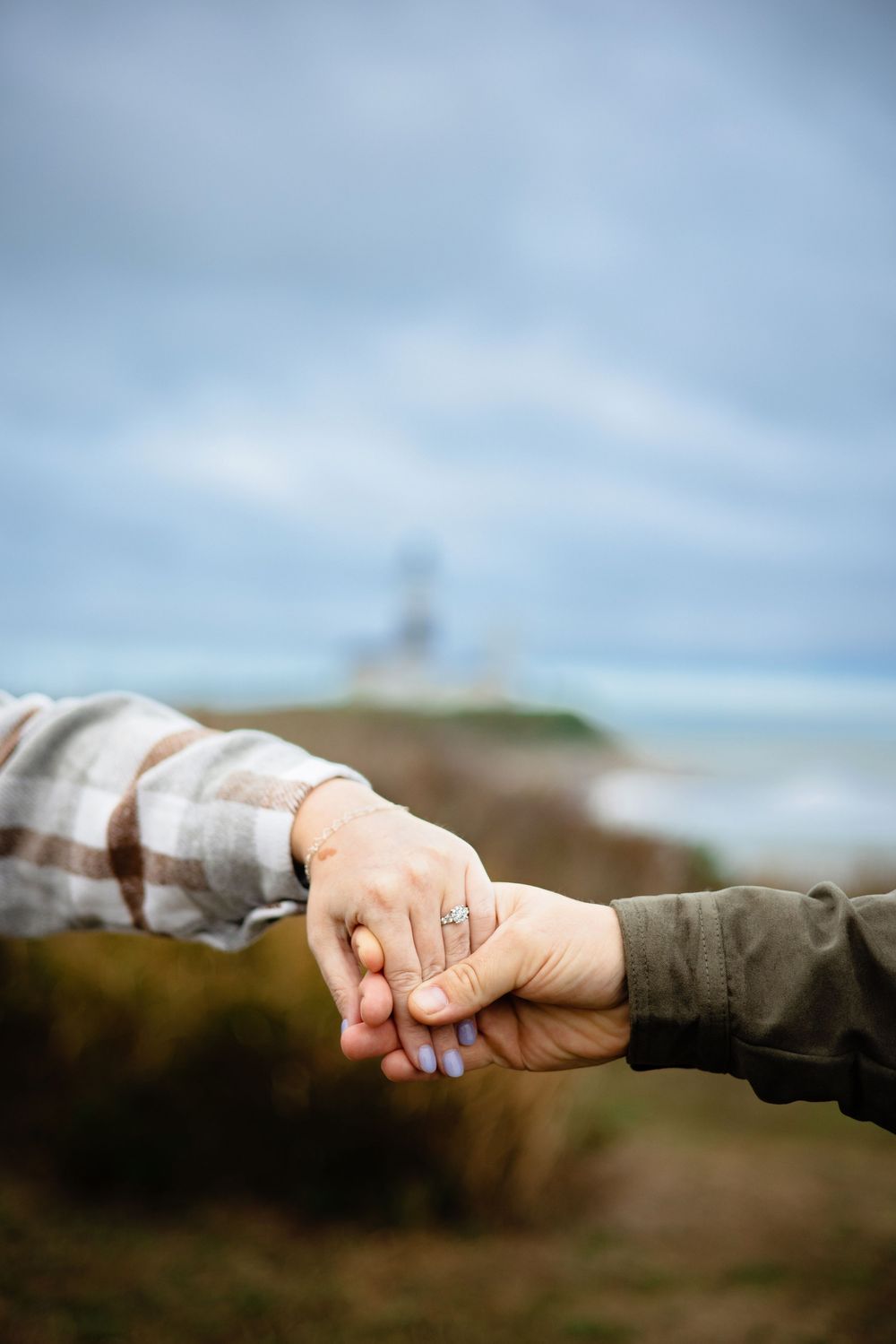 Two hands reaching out and holding each other against a blurred natural outdoor background.