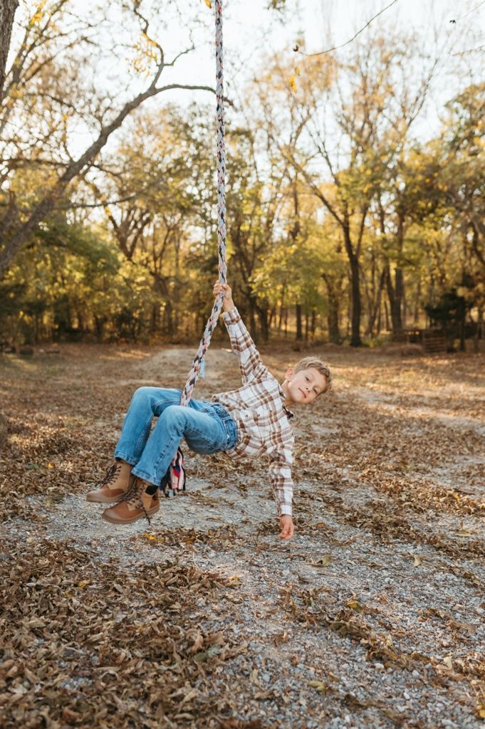 A playful sequence shows someone rolling and tumbling through autumn leaves in a sunlit wooded area at golden hour.