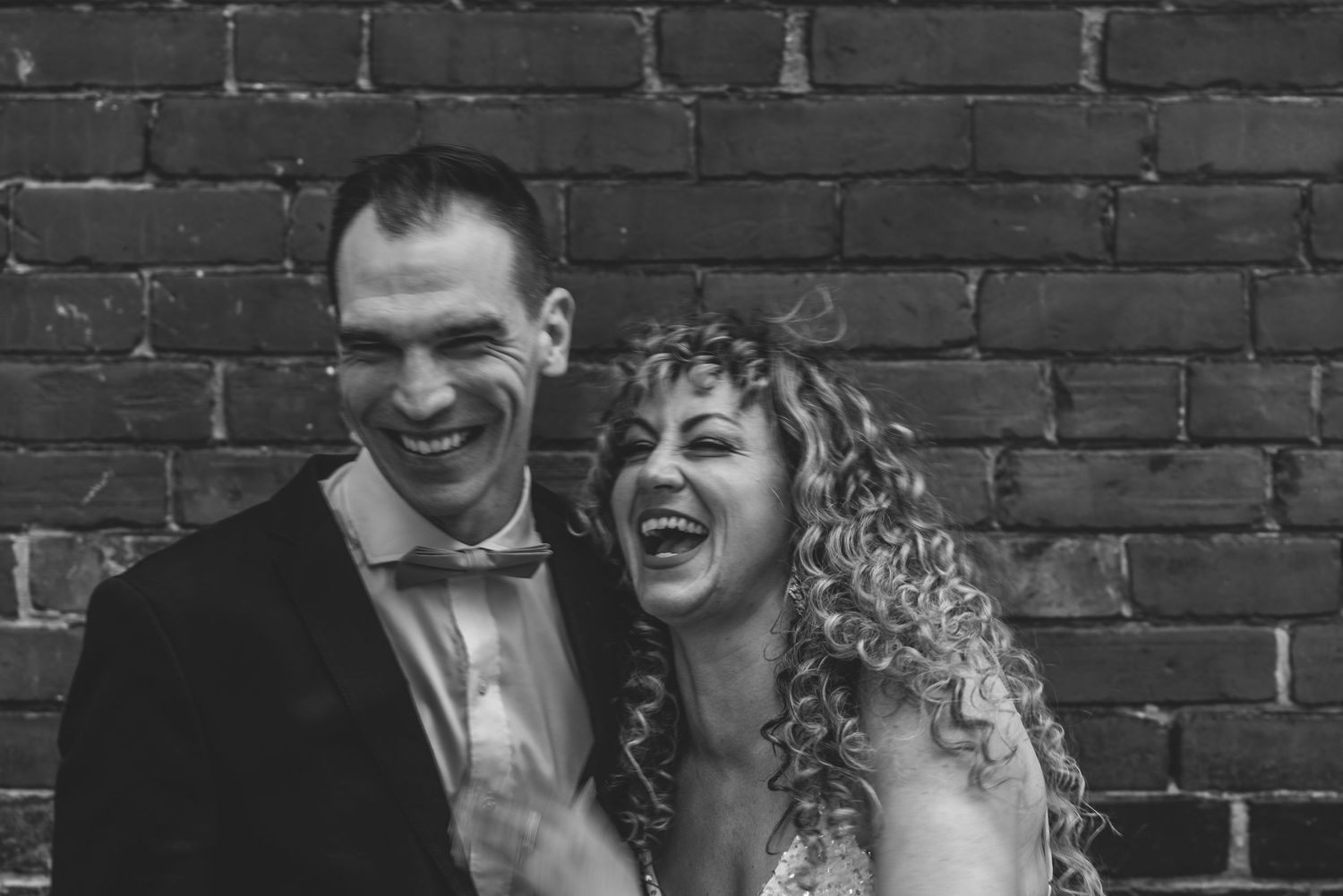 Bride and groom laughing together during relaxed wedding portrait session.