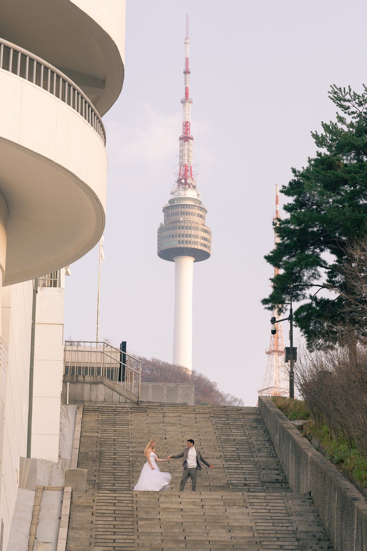 Stone steps lead up to N Seoul Tower in South Korea with curved white architecture and communication towers visible.