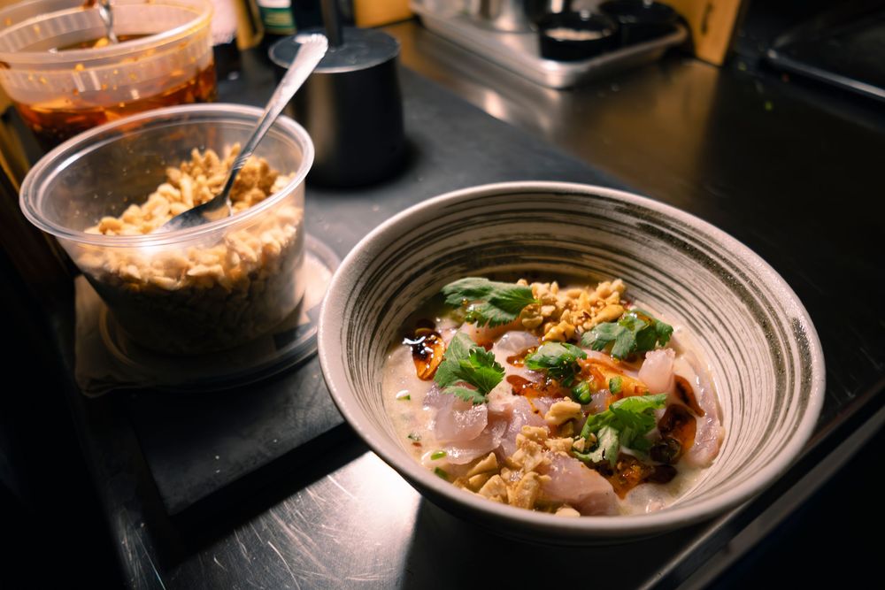 Beautifully plated seafood dish with colorful garnishes in a textured ceramic bowl.