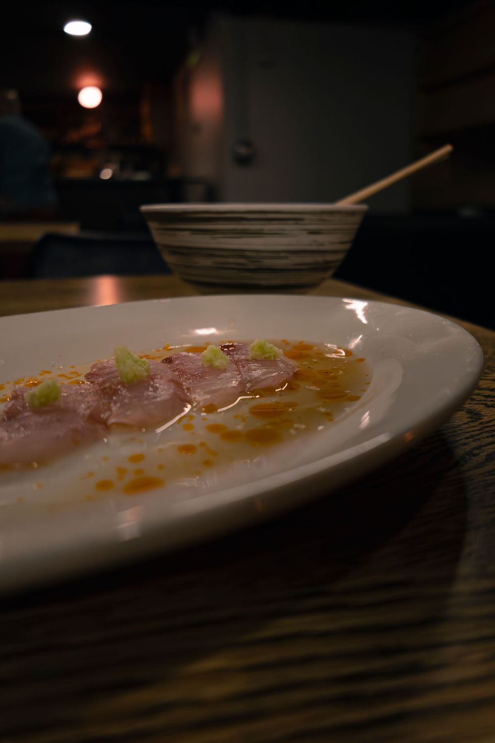Close-up view of a white plate with garnished food in a dimly lit setting.