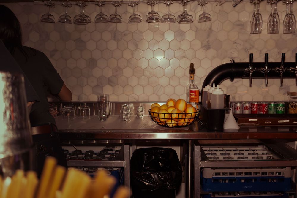 Dimly lit bar interior with decorative hexagon tile pattern on wall.