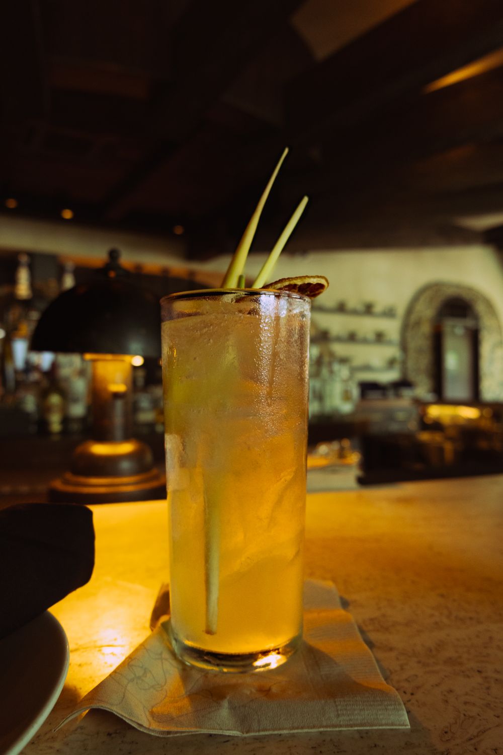 Craft cocktails with garnishes served on elegant coasters in a moody bar atmosphere.