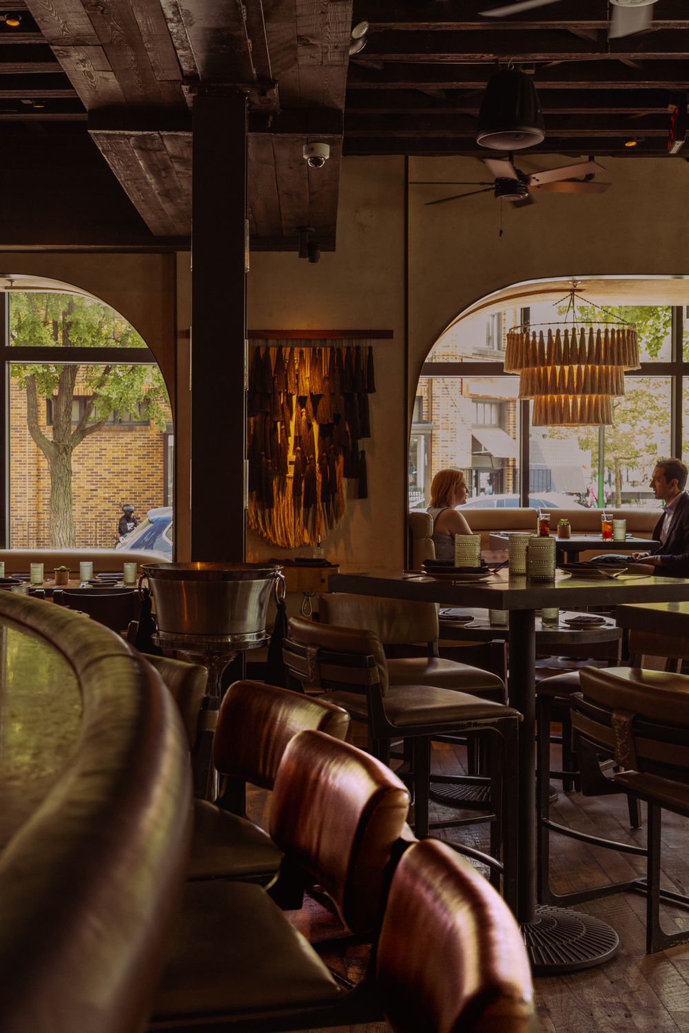 Rustic restaurant interior with leather booth seating and wooden accents illuminated by natural light through windows.