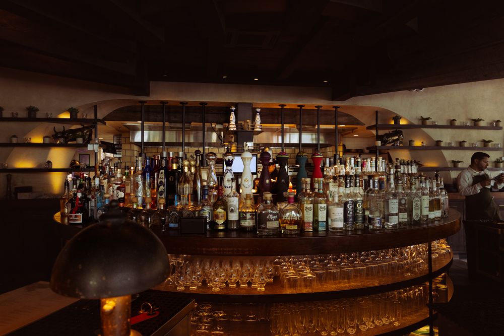 Panoramic view of a well-stocked bar with extensive bottle display and ambient lighting.