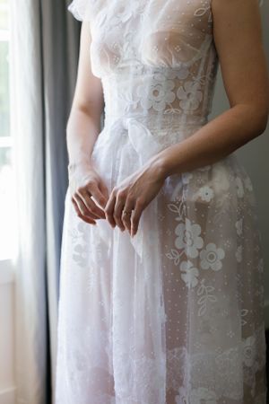 Close-up detail of a delicate white lace wedding dress with floral patterns.