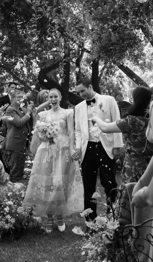 Wedding celebration in a garden setting with guests showering confetti on the newlyweds.