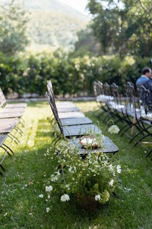 Metal folding chairs arranged on lawn with delicate white flower arrangements.