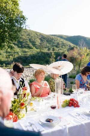 Elegant outdoor wedding reception with parasol decorations and mountain views.