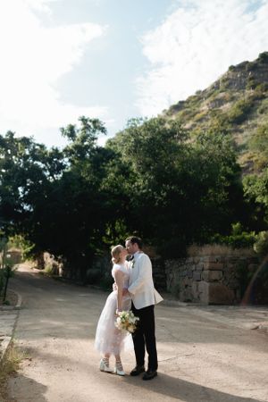 Romantic wedding portrait on a path with mountain backdrop and natural lighting.