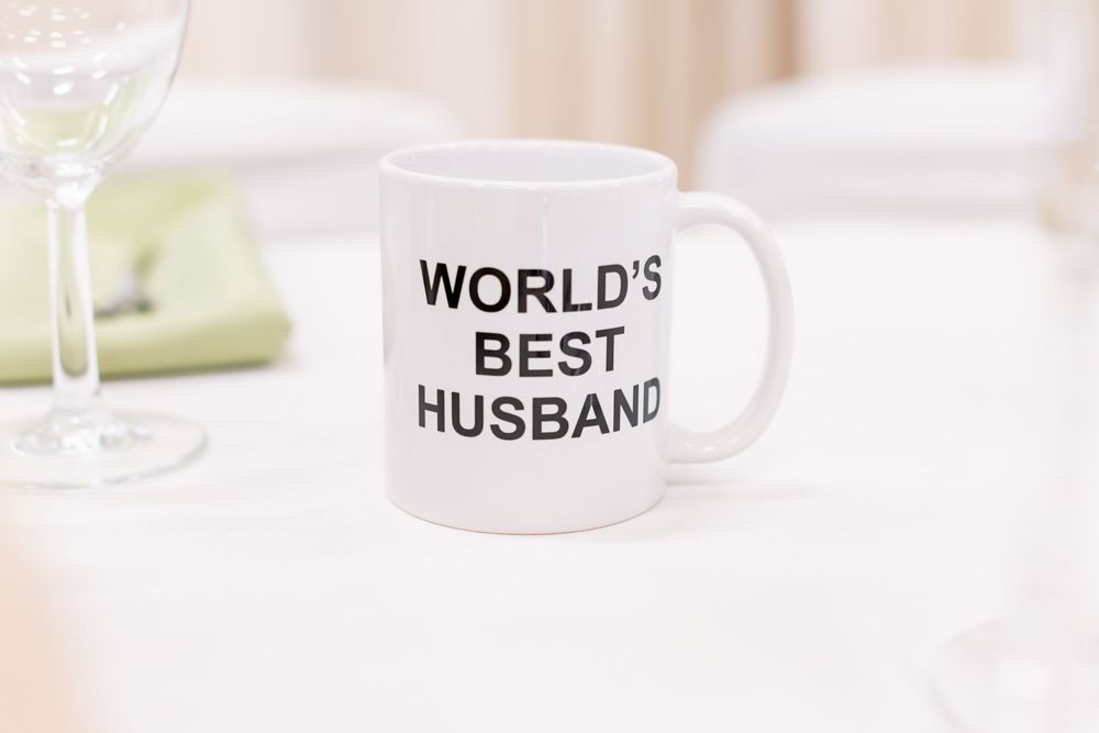 Three white ceramic mugs with text displayed in a row on a light colored surface.