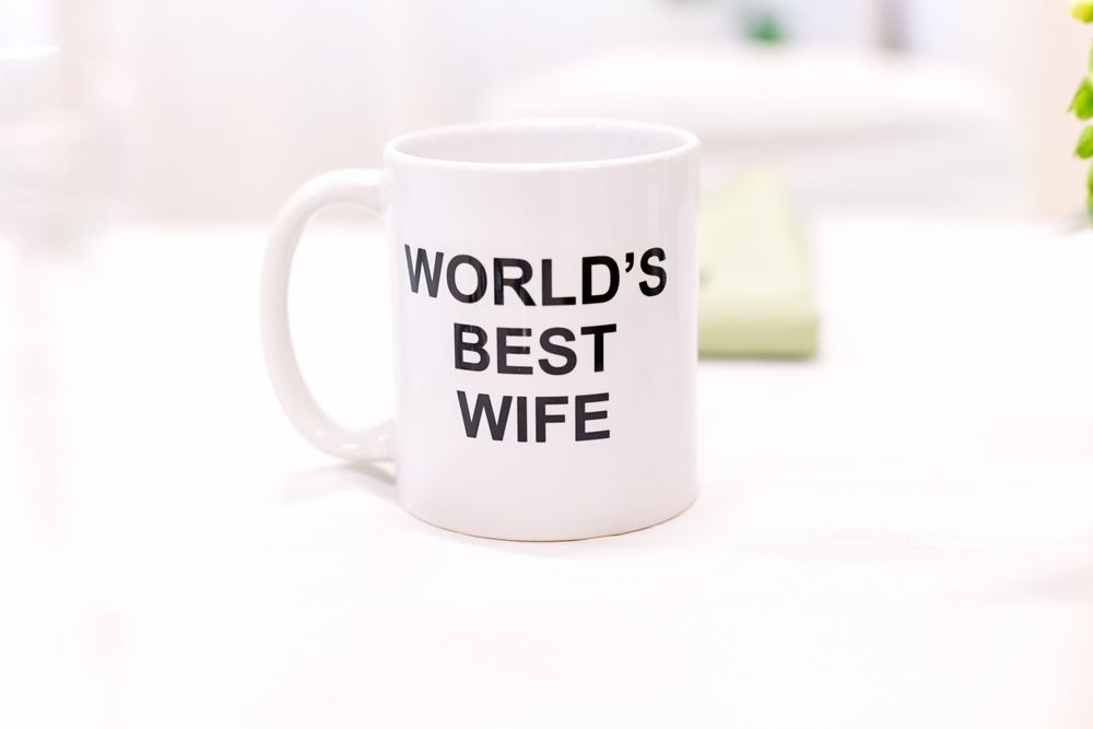 White ceramic coffee mugs with text 'World's Best Wife' arranged in a row on a white surface.