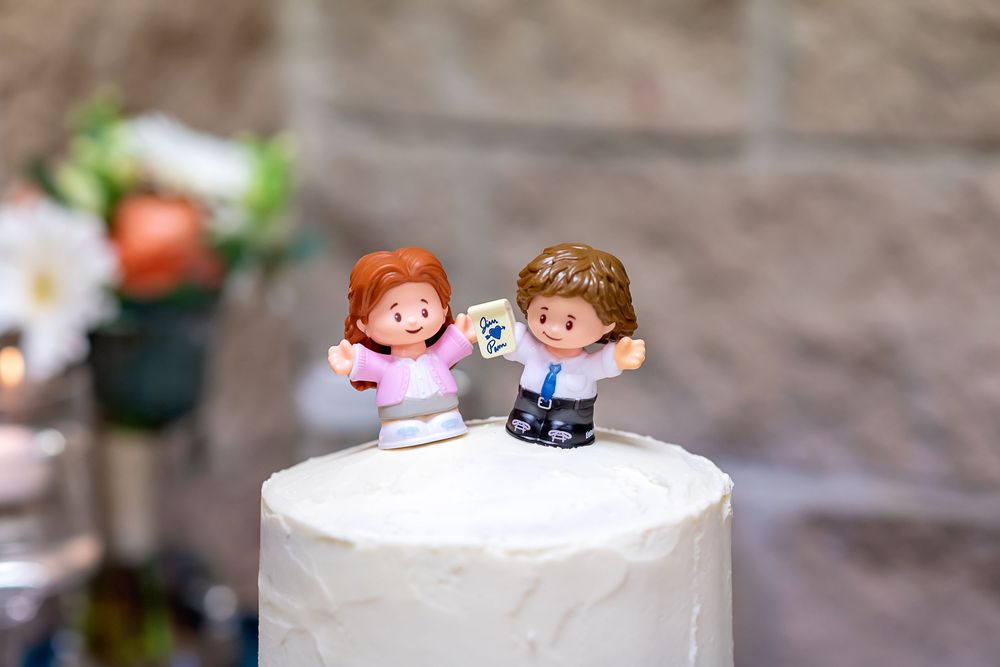 A series of wedding cake decorations showing cats and cartoon figures displayed on white frosted tiers.