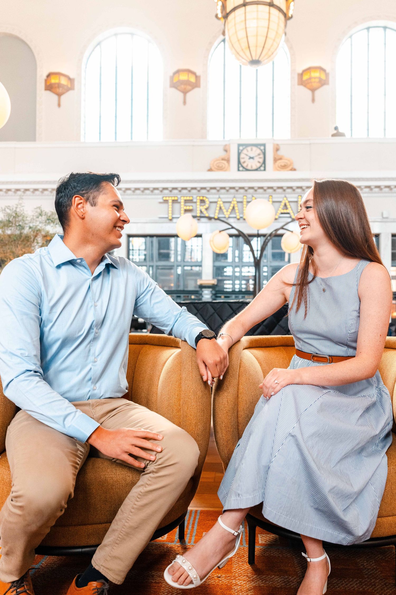 Couple sitting and smiling at each other inside Denver Union Station terminal building.