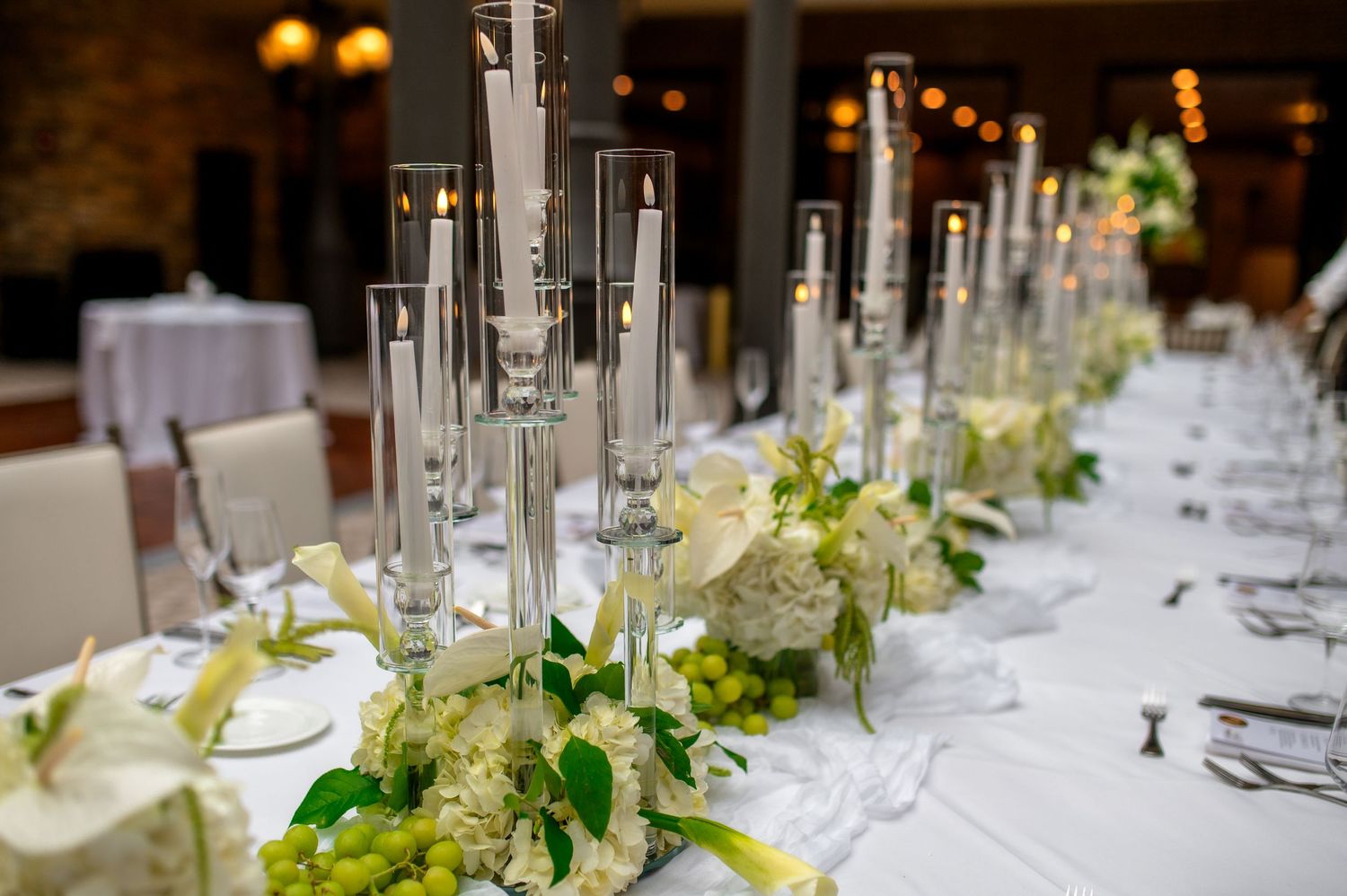 Elegant table setting with white roses, wine bottle, and black charger plates at formal dinner event.