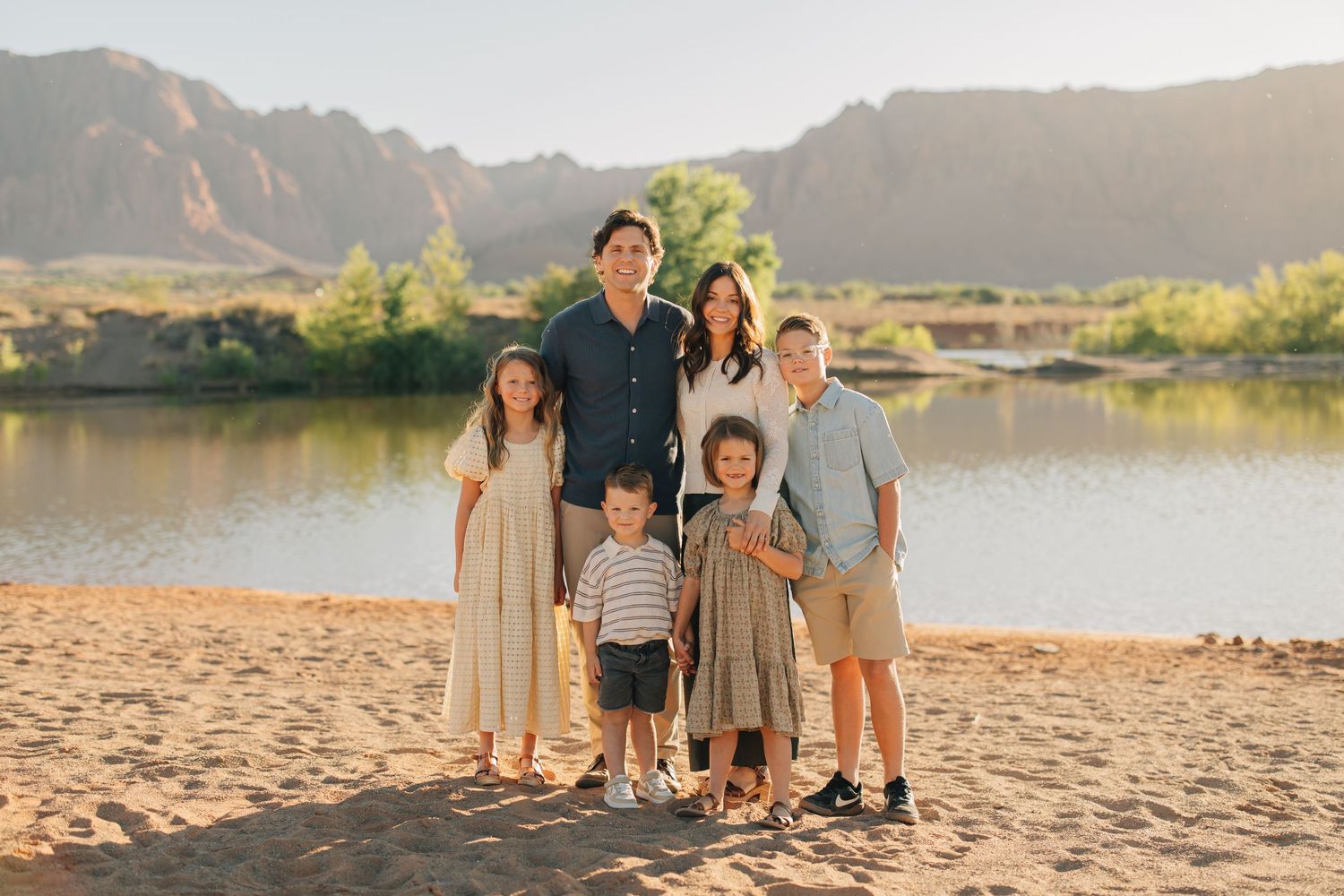 A series of group photos taken at sunset against stunning red rock cliffs and a lake in the background.