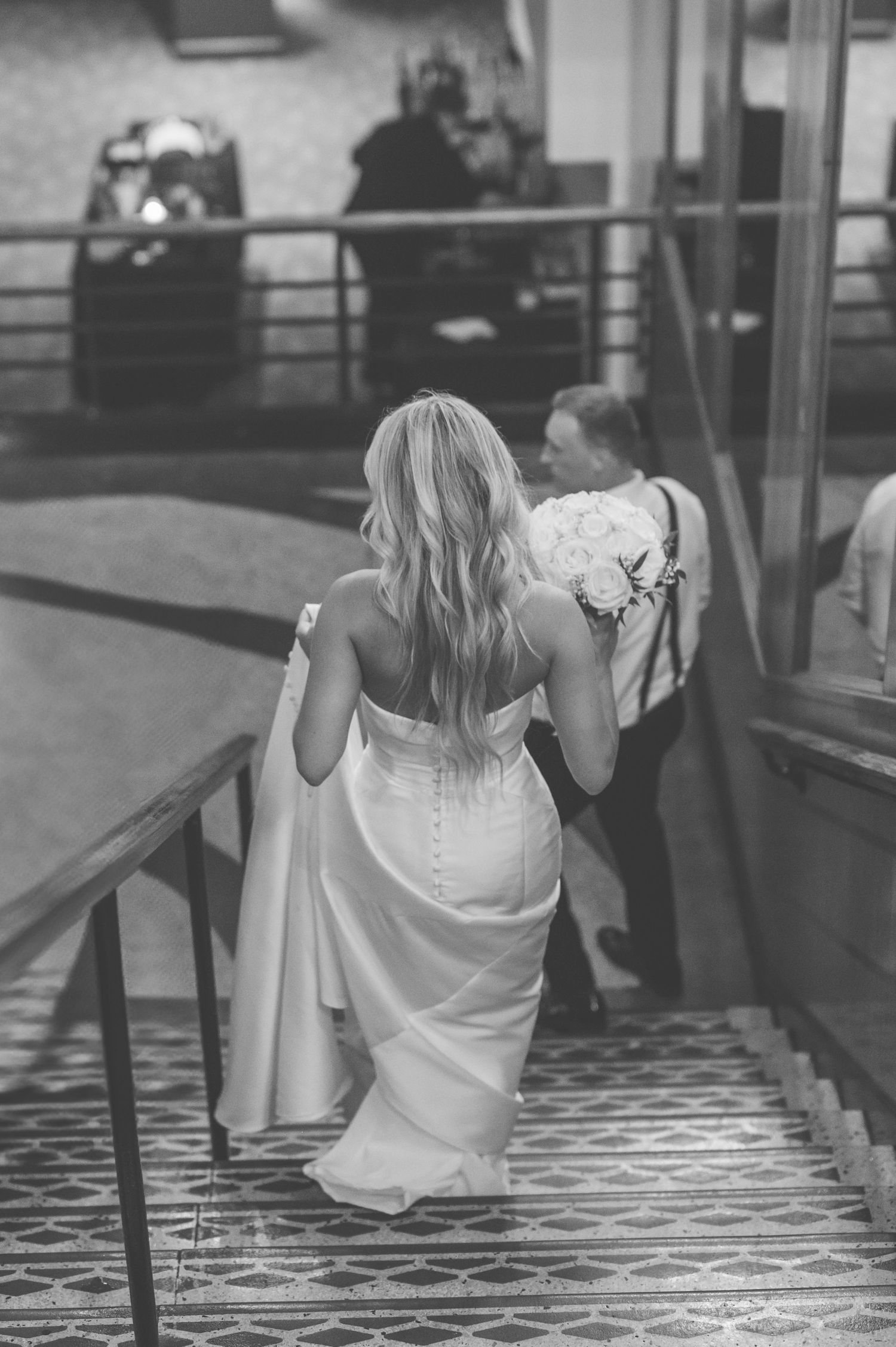 A series of black and white photos showing someone in a white dress sitting and posing on reflective stairs.