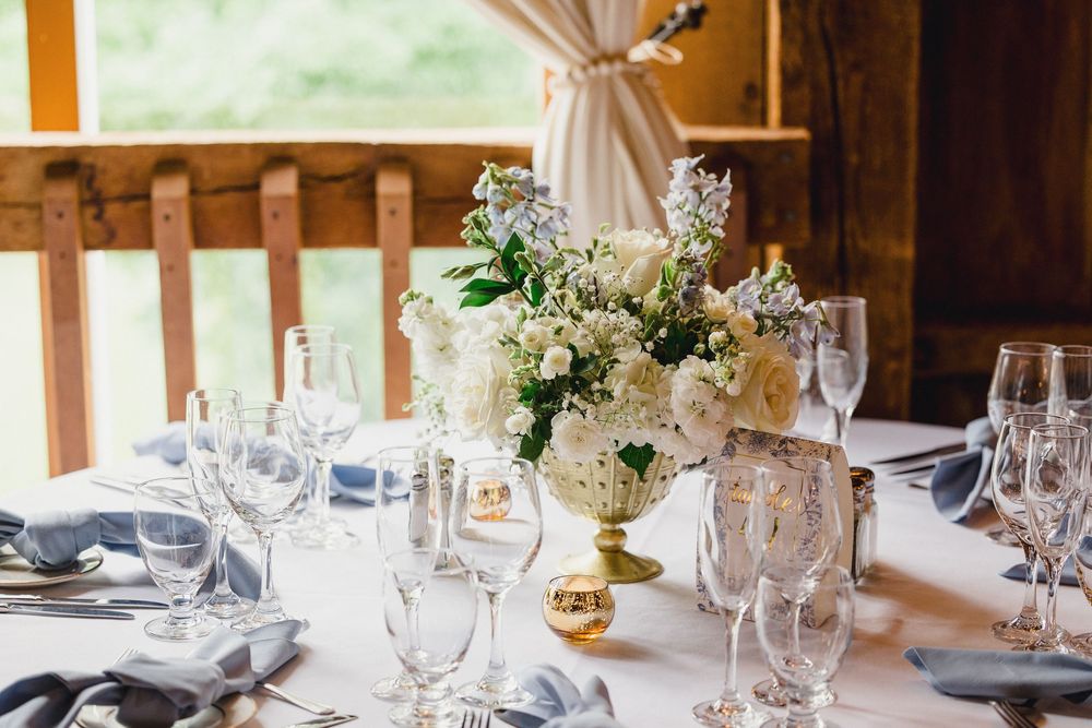 Elegant table settings with wine glasses and floral centerpieces in a rustic wooden venue.
